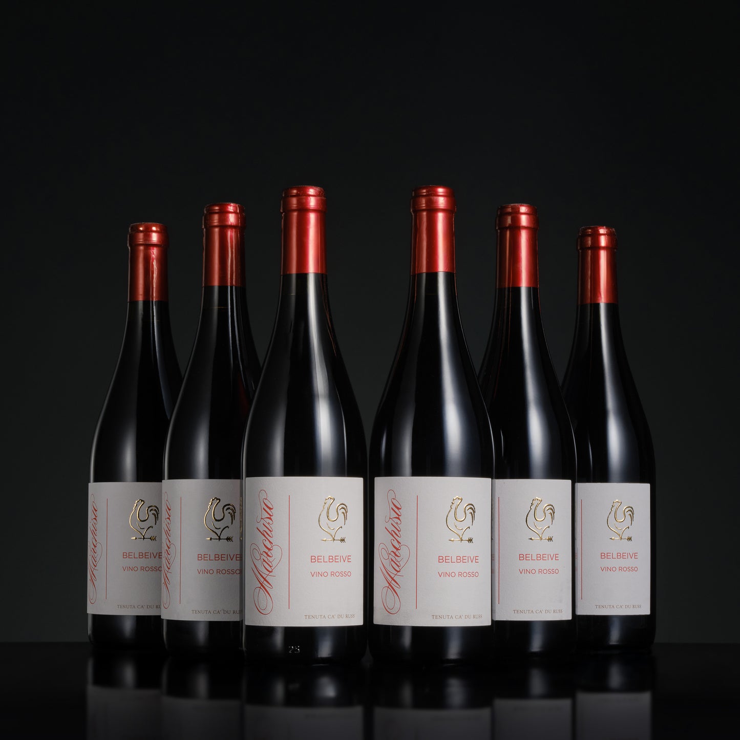 Six bottles of Delinero wine with red foil caps on a black background