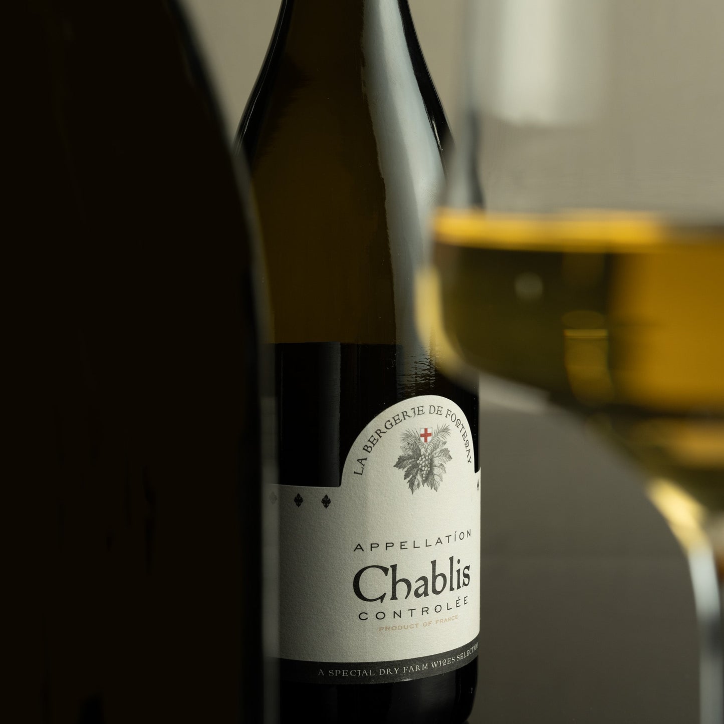 Chablis wine bottle with a glass of wine in the background