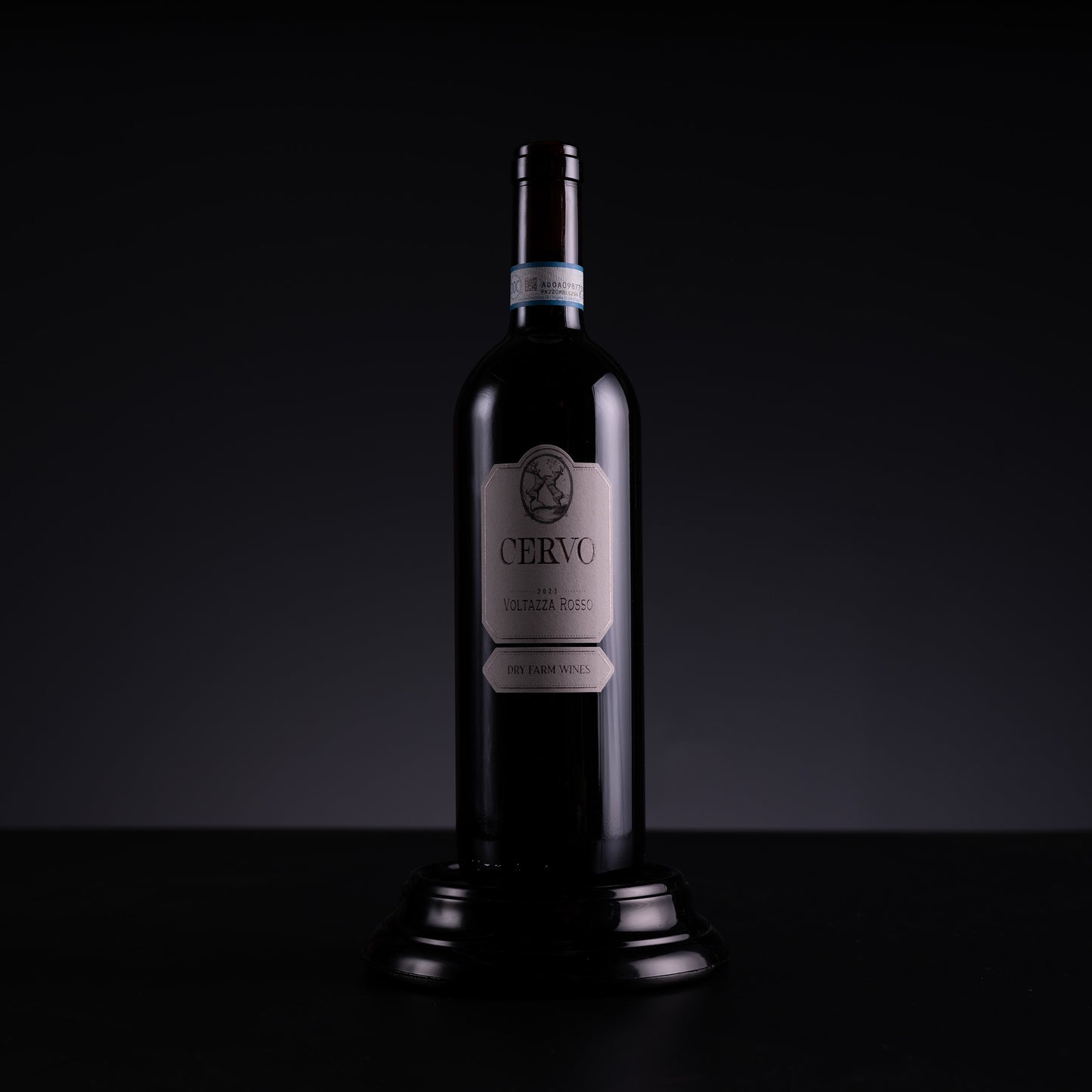A dark glass bottle of Cervo Pinot Noir red wine, displayed on a small black pedestal against a dark studio background.
