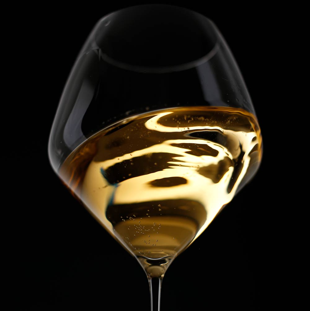 close up of white wine in a glass with dark background