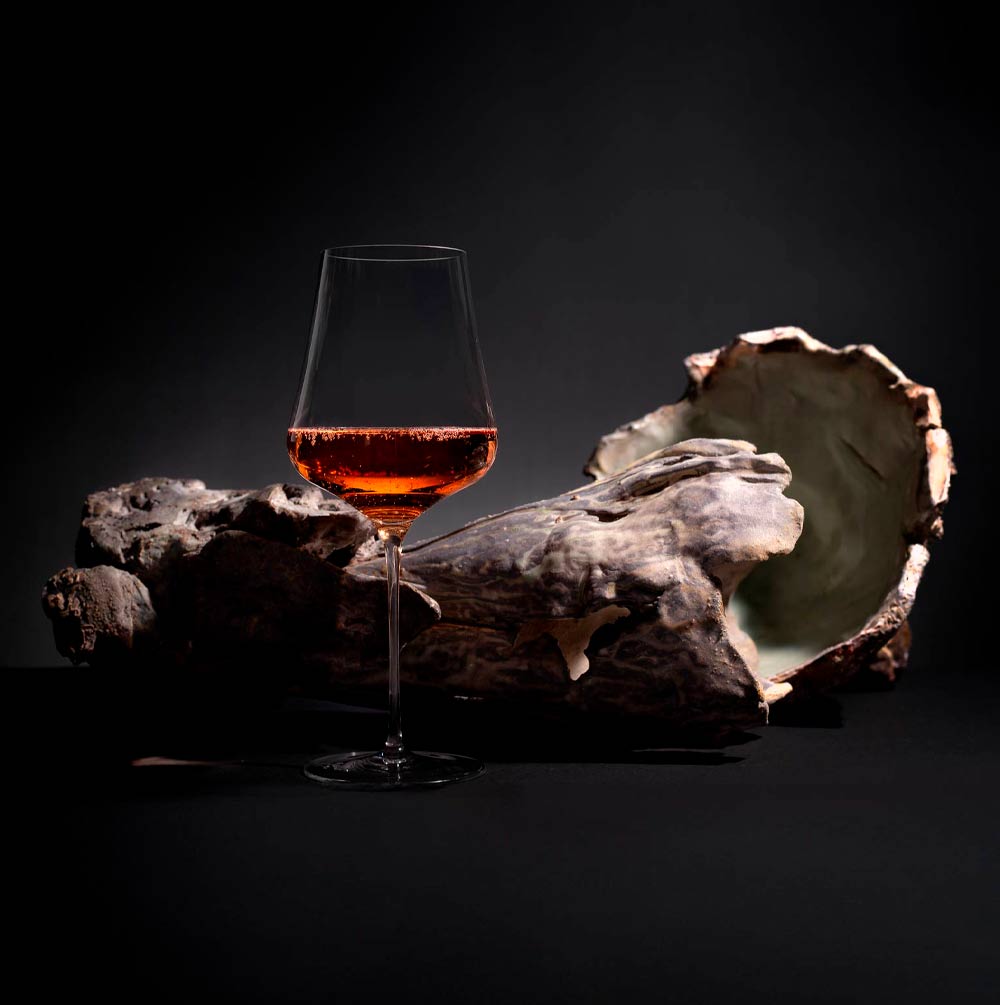 glass of rose in front of petrified wood art with dark background