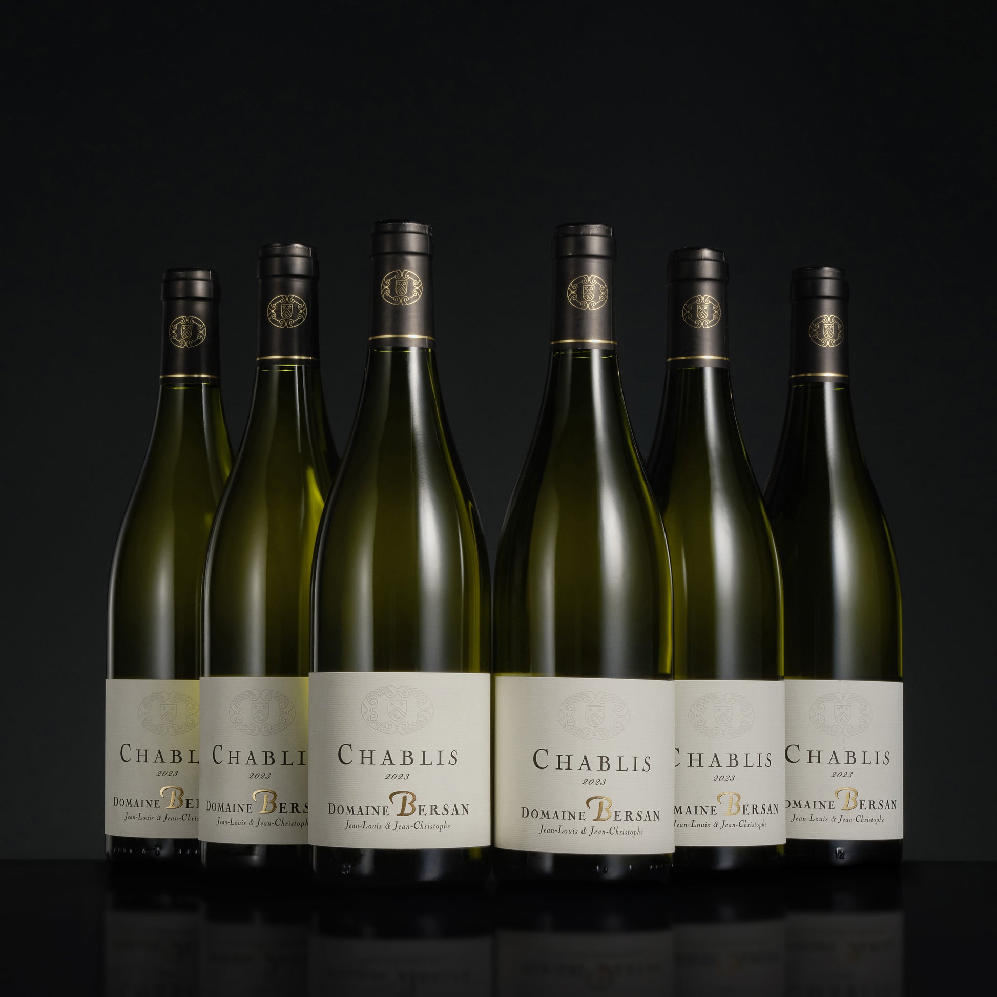 Six bottles of Domaine Bersan Chablis wine on a black background