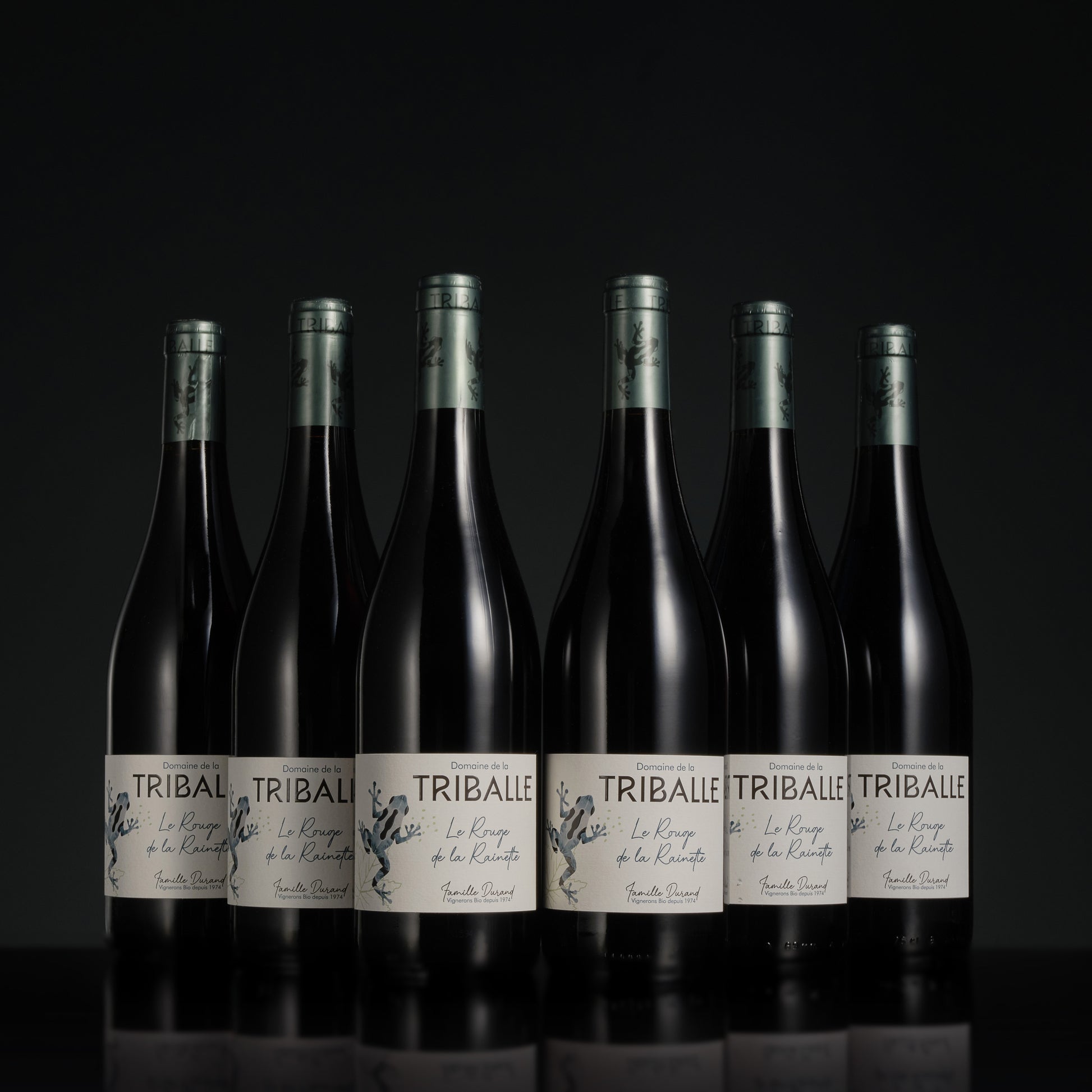 Row of Tribale wine bottles on a black background