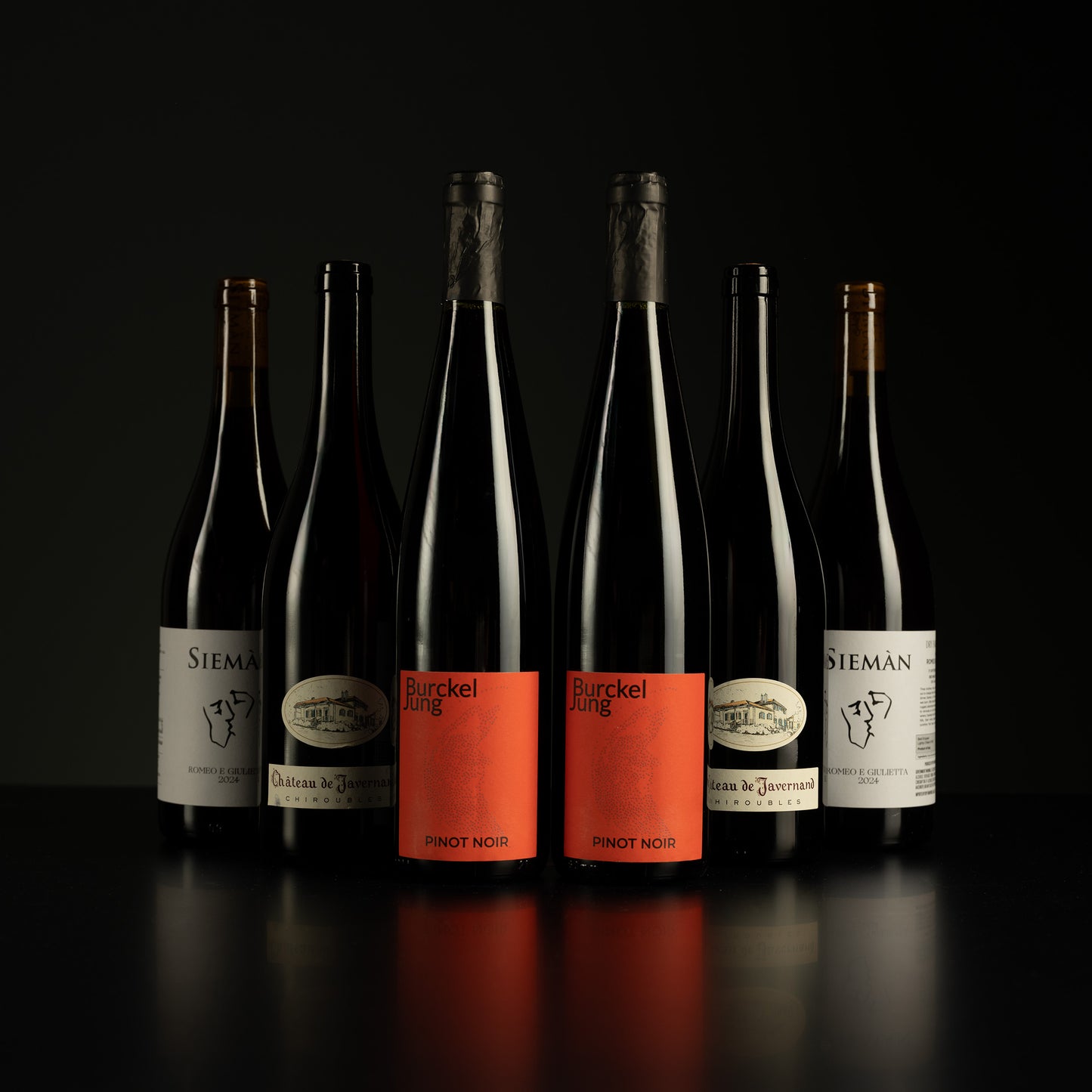 Row of wine bottles with visible labels on a dark background