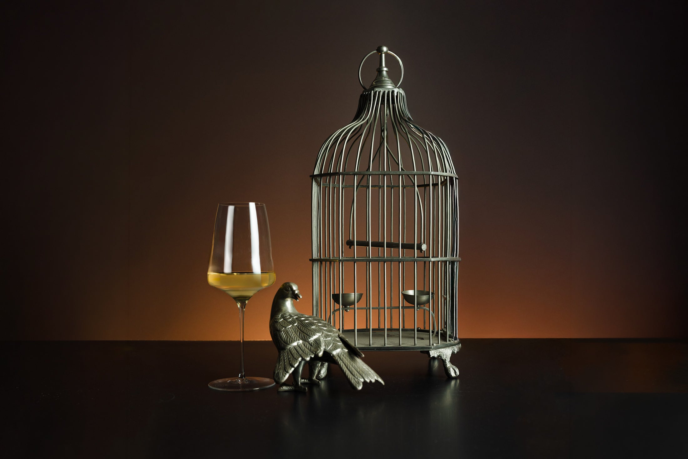 Glass of white wine with bird cage sculpture