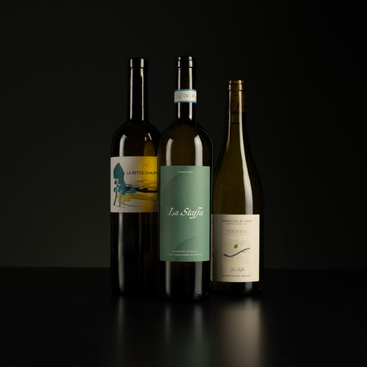 Three wine bottles with labels on a dark background