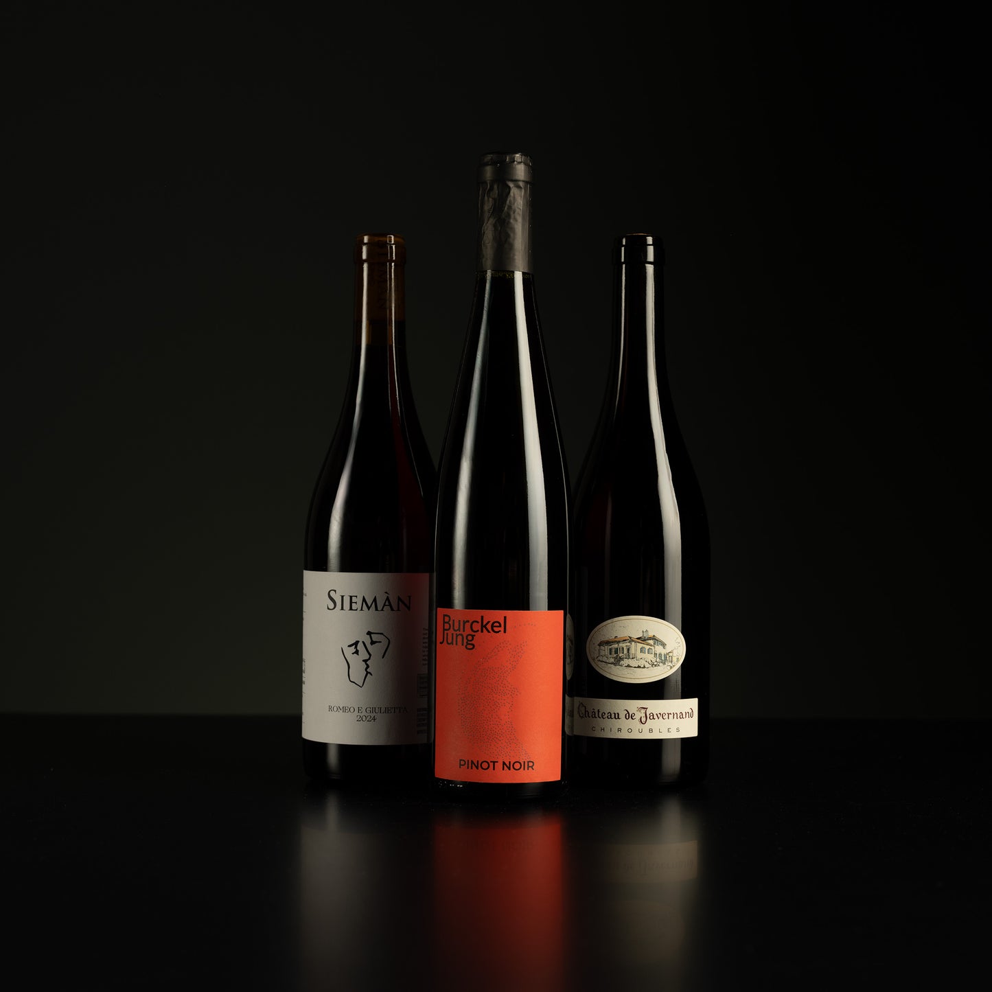 Three wine bottles with labels on a black background
