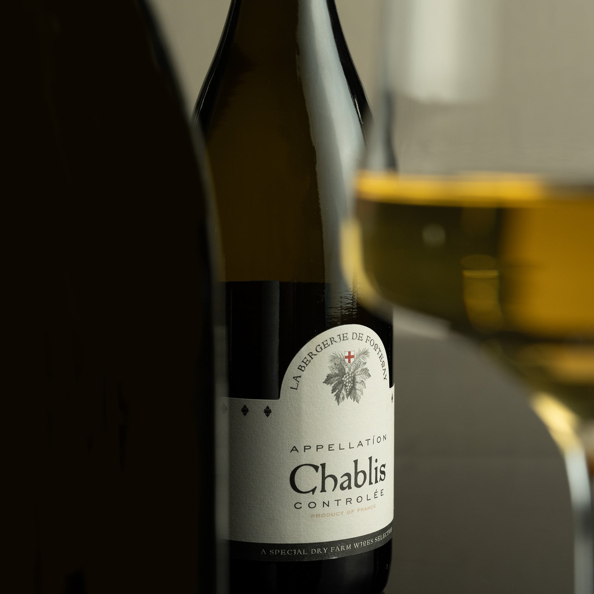 Chablis wine bottle with a glass of wine in the background