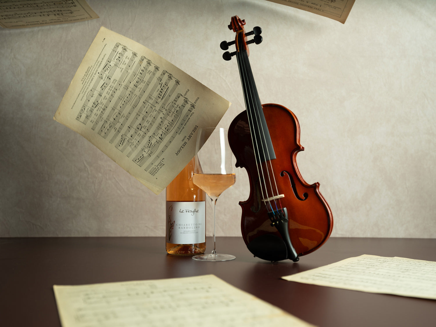 Violin on a table with sheet music and a glass of wine
