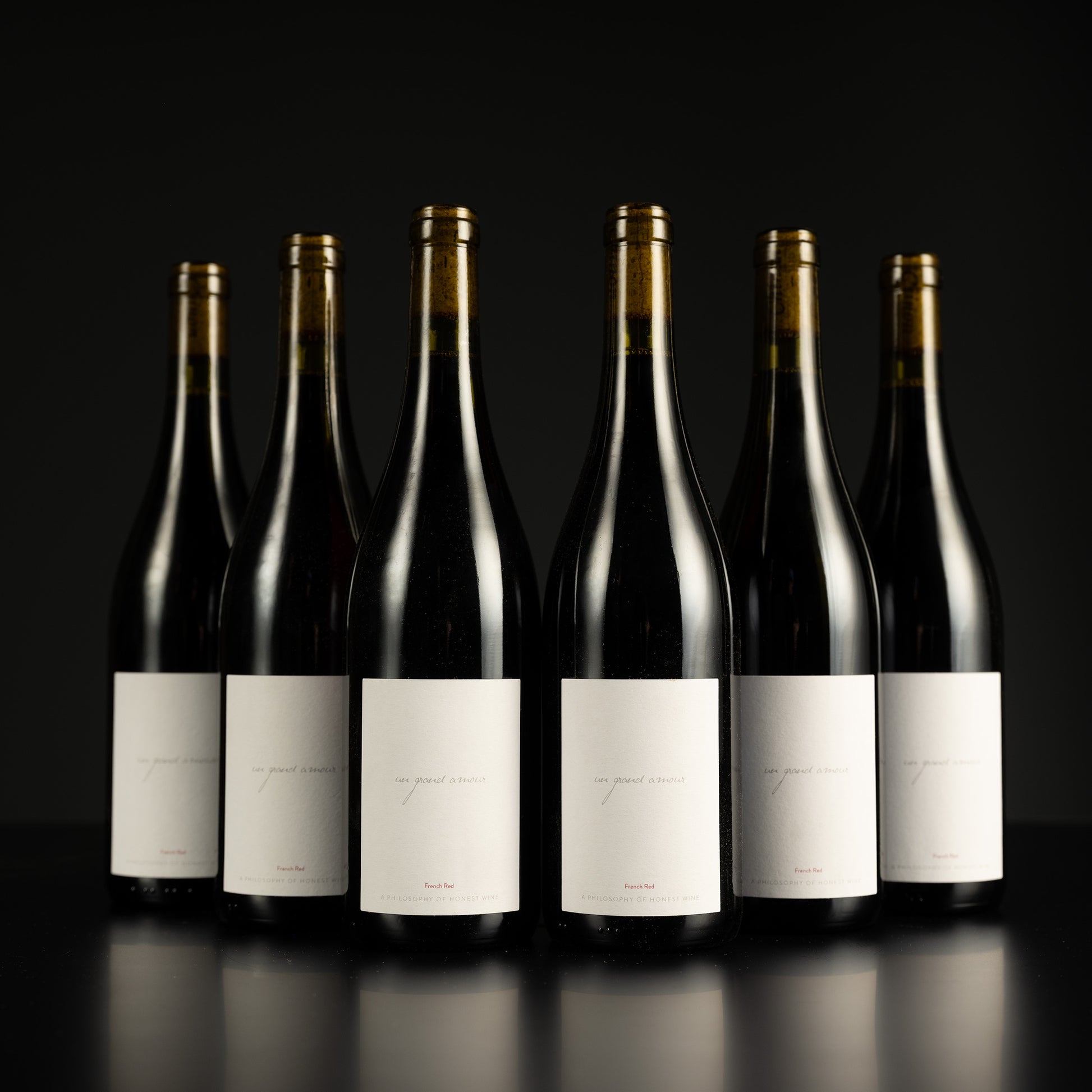 Six wine bottles with labels on a black background
