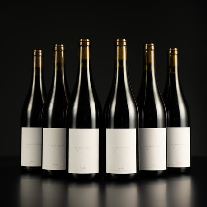 Six wine bottles with labels on a black background