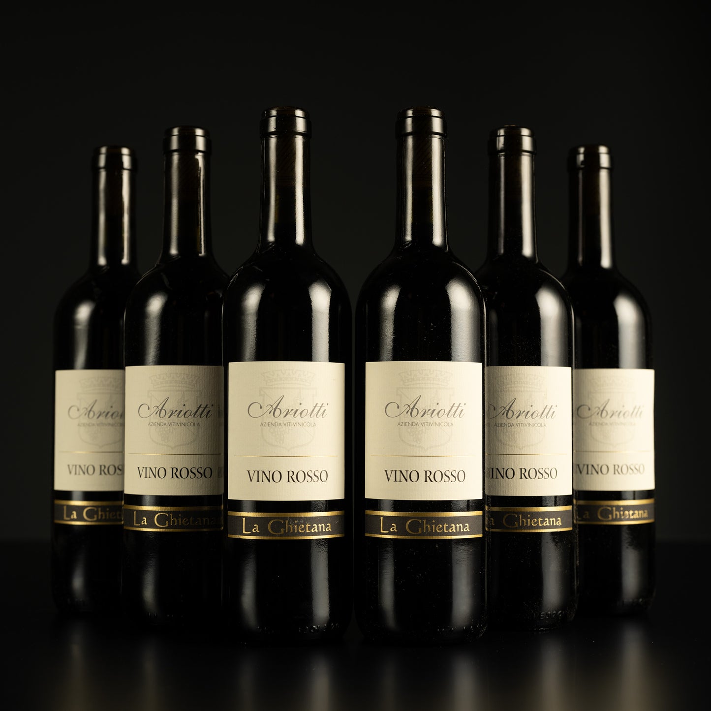 Row of Arietti Vino Rosso wine bottles on a black background
