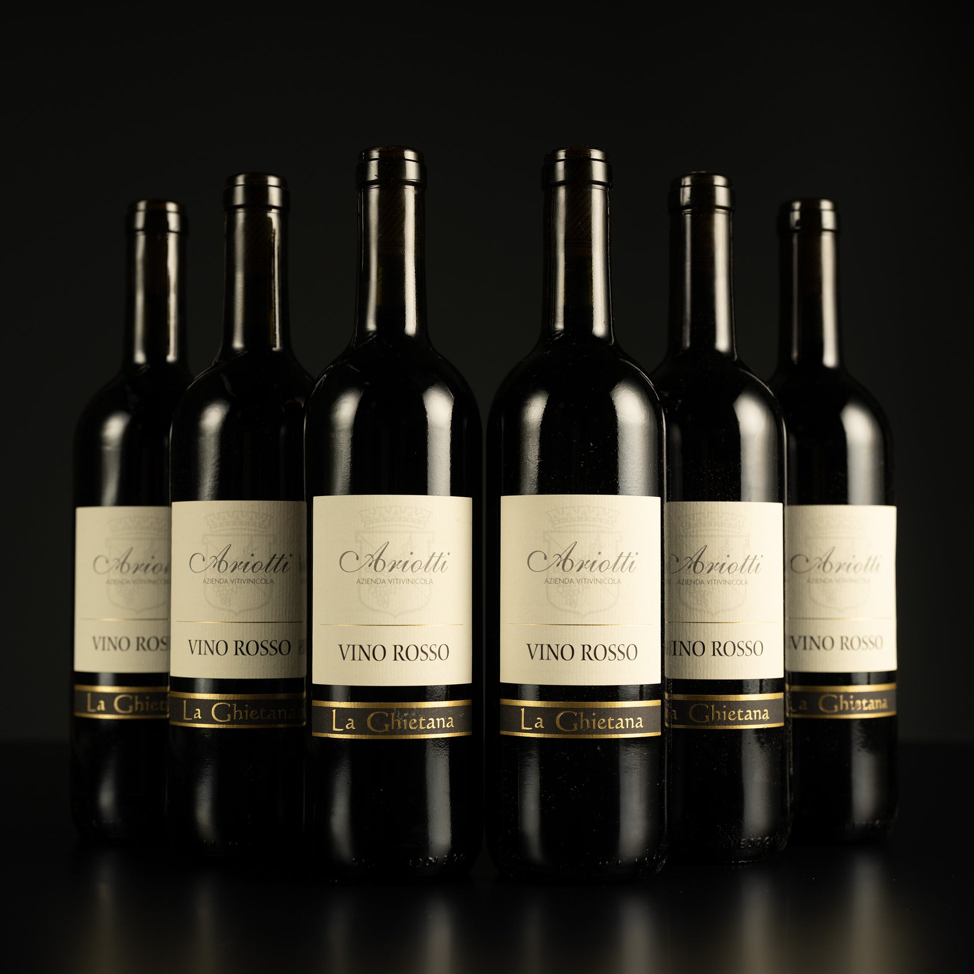 Row of Arietti Vino Rosso wine bottles on a black background