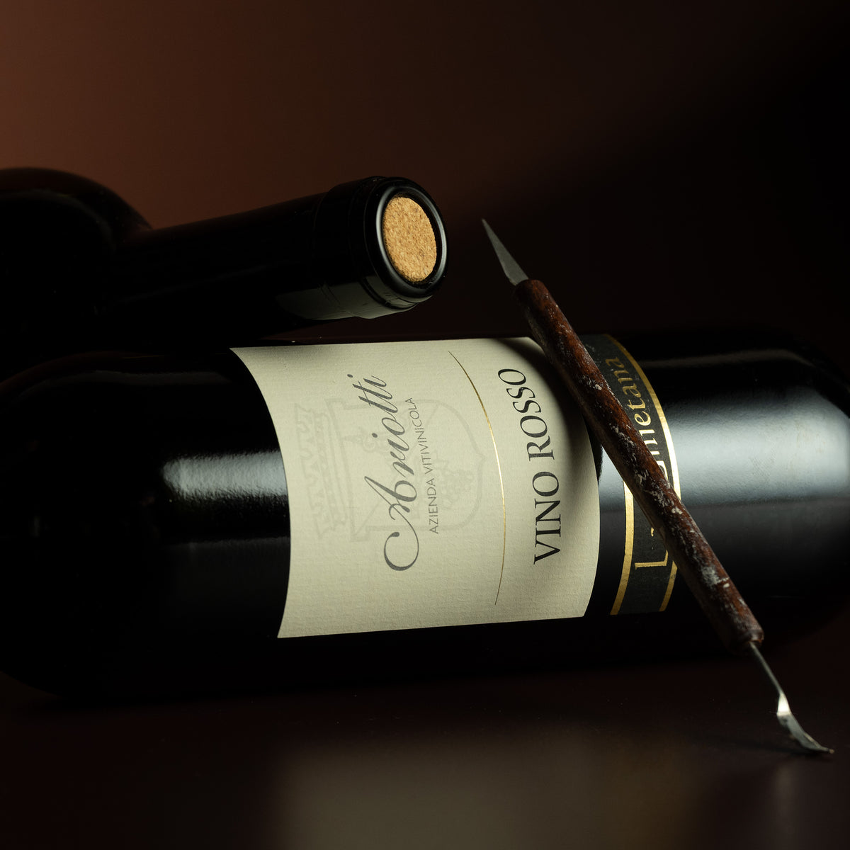 Wine bottle labeled 'Vino Rosso' with a cork and a spoon on a dark background