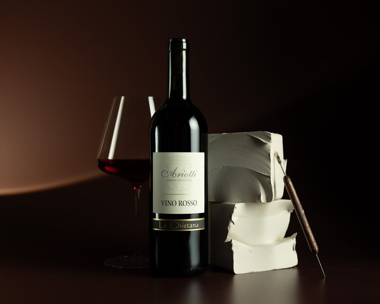 Red wine bottle with a glass and ice cubes on a dark background