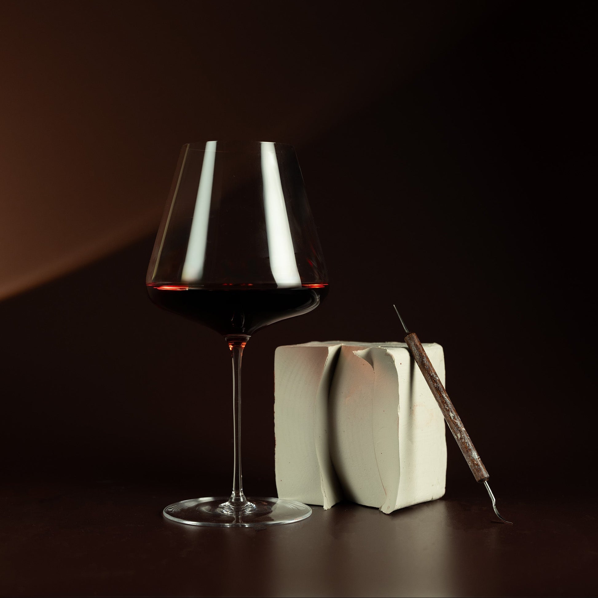 Glass of red wine with a book and pen on a dark background