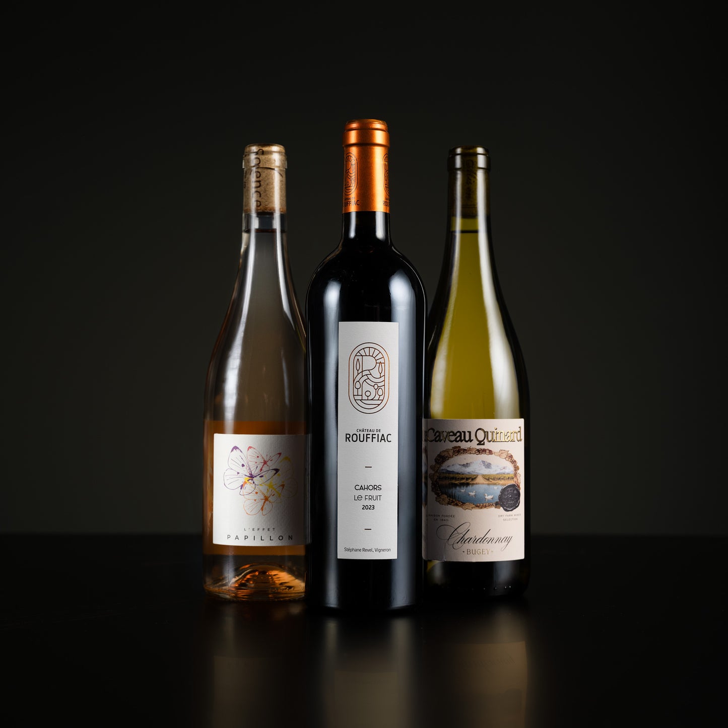Three wine bottles with labels on a dark background