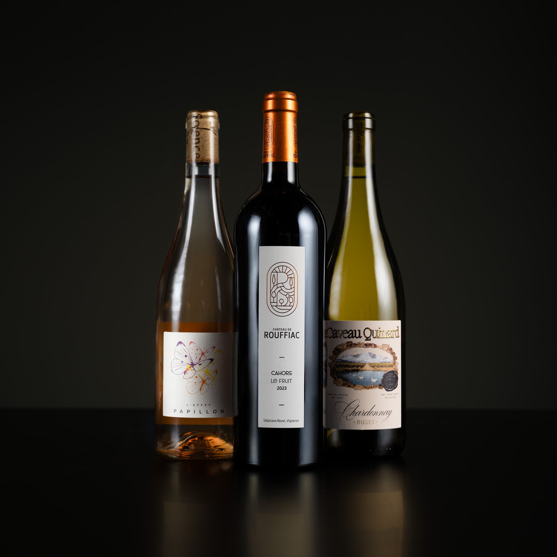 Three wine bottles with labels on a dark background