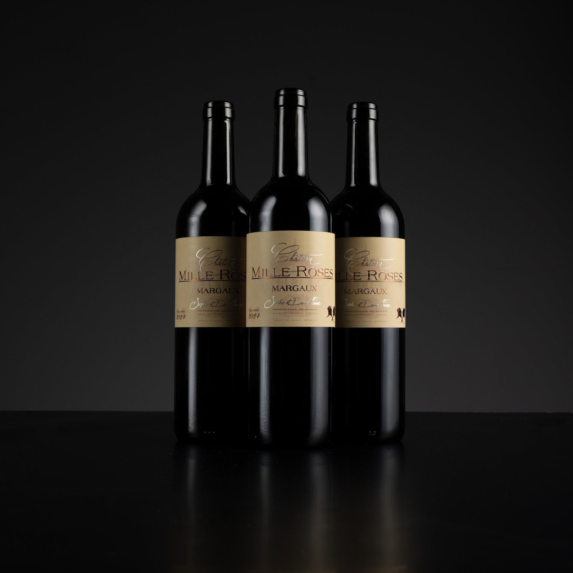Three bottles of Mille Roses Margaux wine on a black background