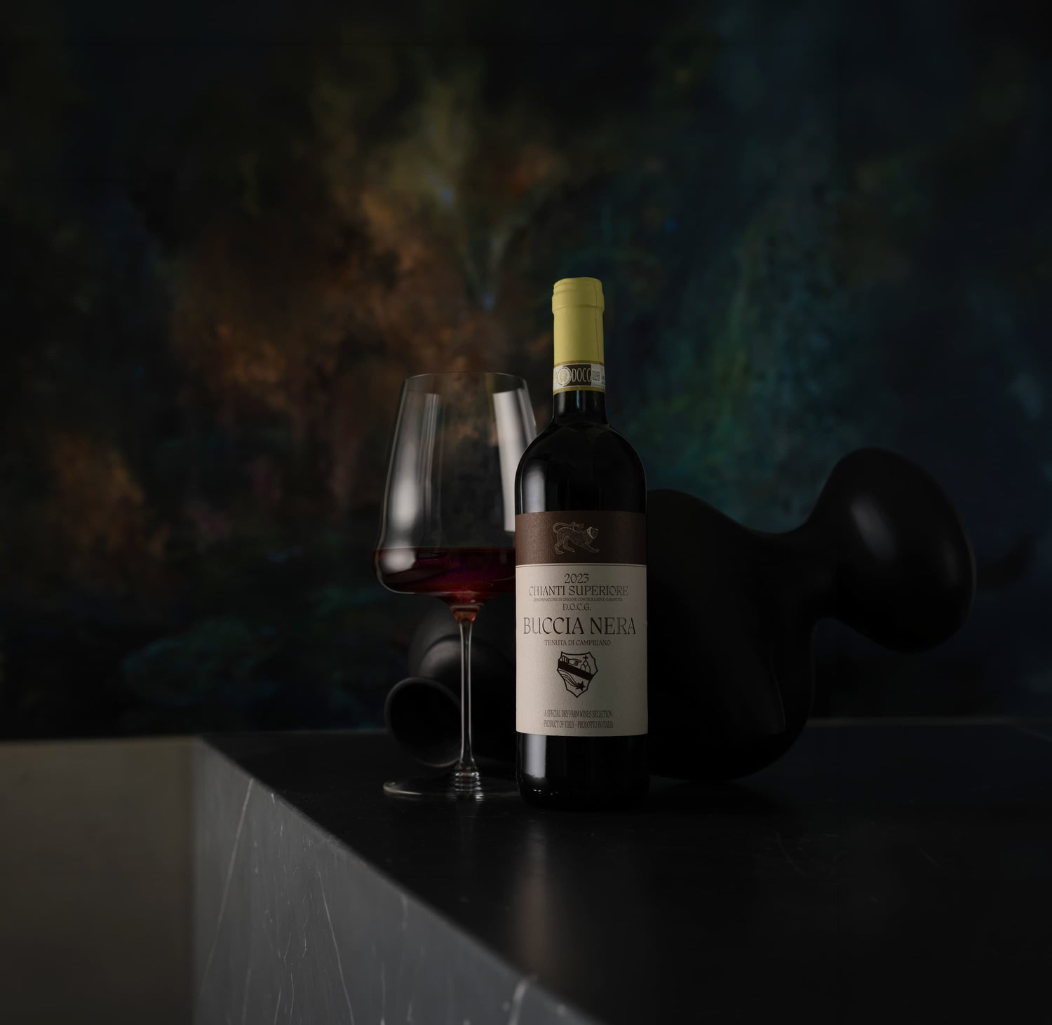 Bottle of wine with a glass on a dark surface against a blurred background