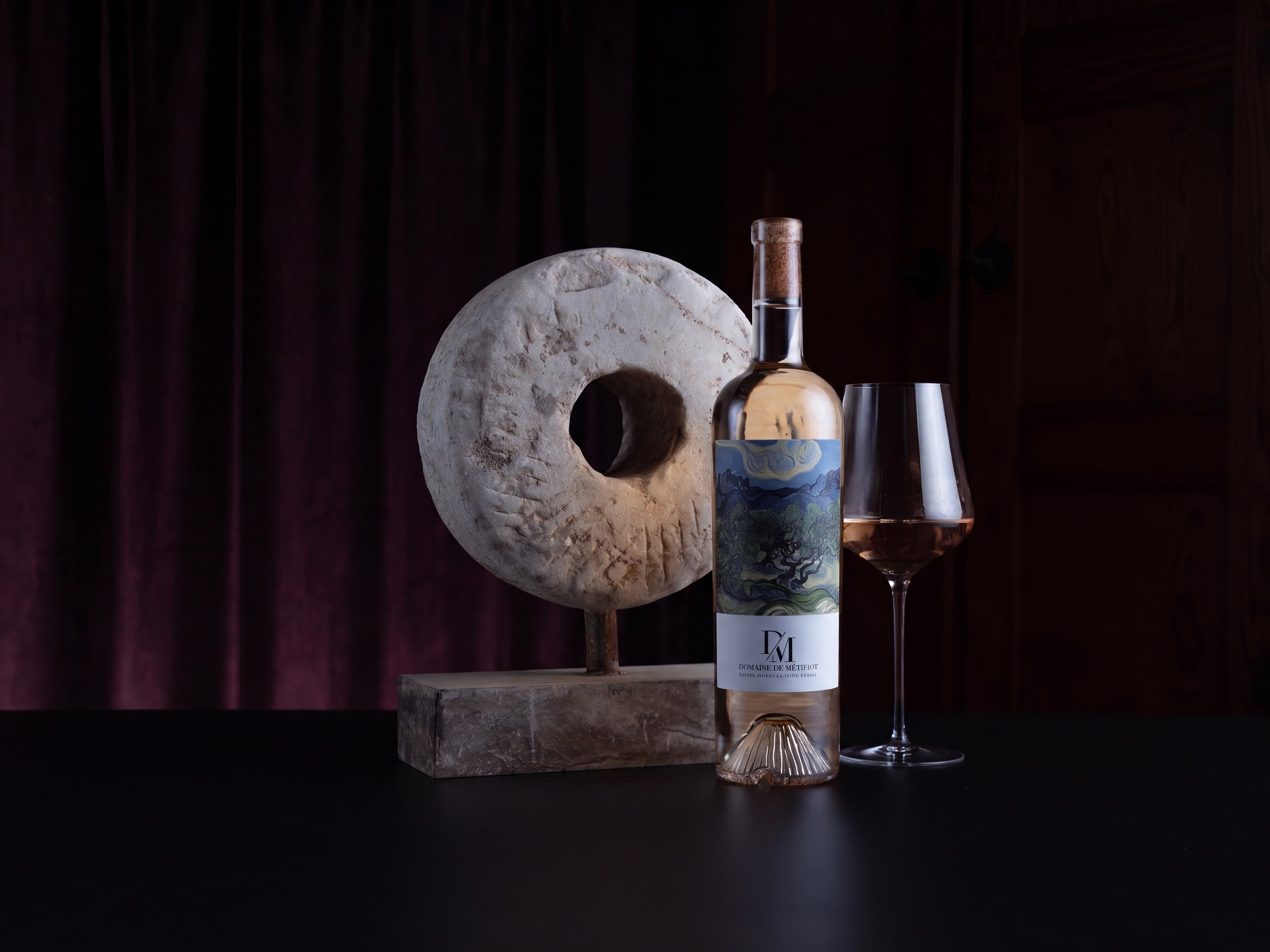 Wine bottle and glass with decorative stone mill on a dark background