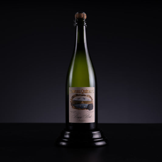 A bottle of Chateau d'Orbassianes Non-Alcoholic Sparkling Wine, displayed on a black stand against a dark studio background.