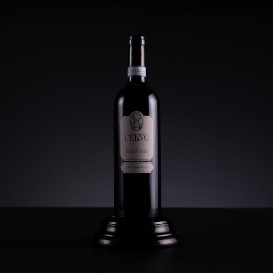 A dark glass bottle of Cervo Pinot Noir red wine, displayed on a small black pedestal against a dark studio background.
