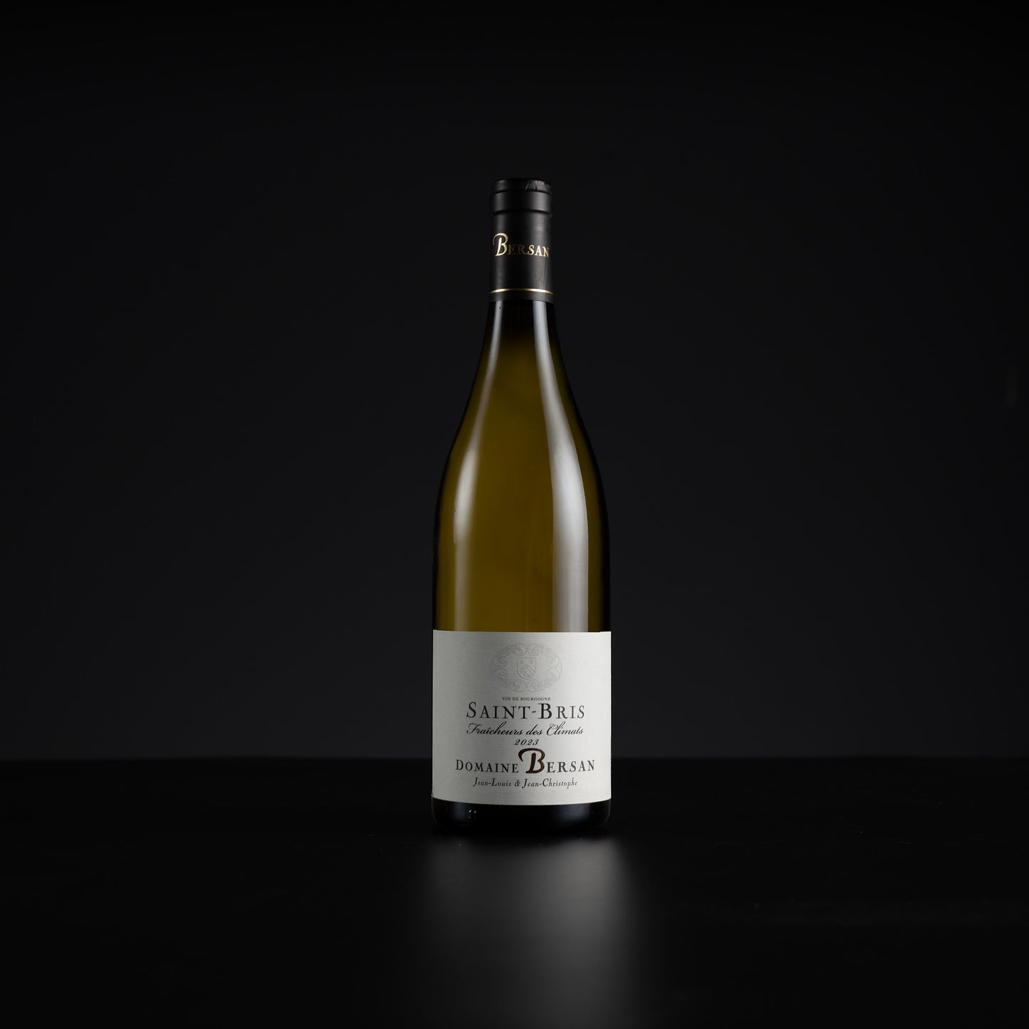 A single bottle of Domaine de Burgan Saint-Bris non-alcoholic white wine, standing upright on a dark reflective surface against a solid black background.