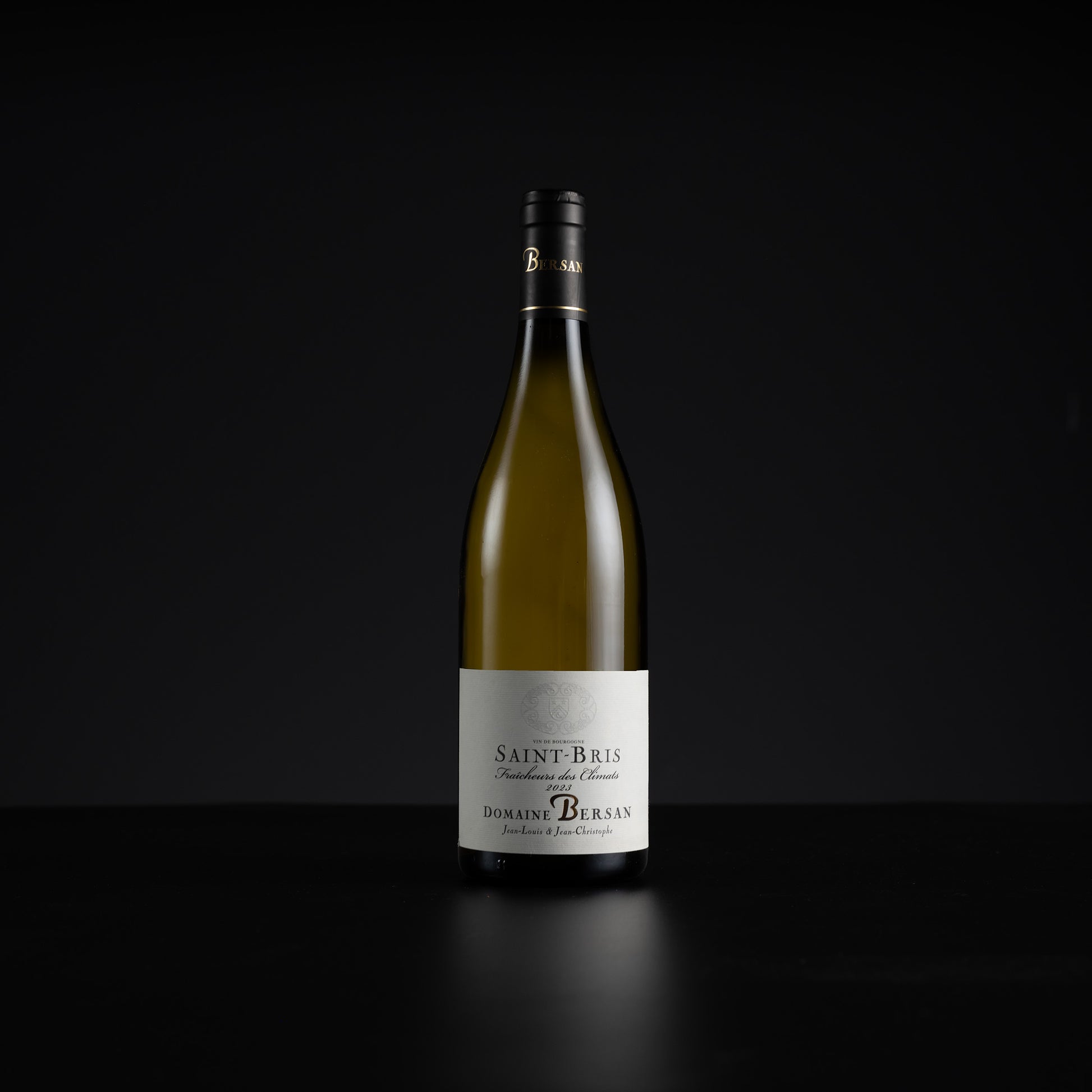A single bottle of Domaine de Burgan Saint-Bris non-alcoholic white wine, standing upright on a dark reflective surface against a solid black background.