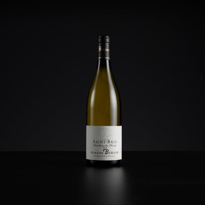 A single bottle of Domaine de Burgan Saint-Bris non-alcoholic white wine, standing upright on a dark reflective surface against a solid black background.