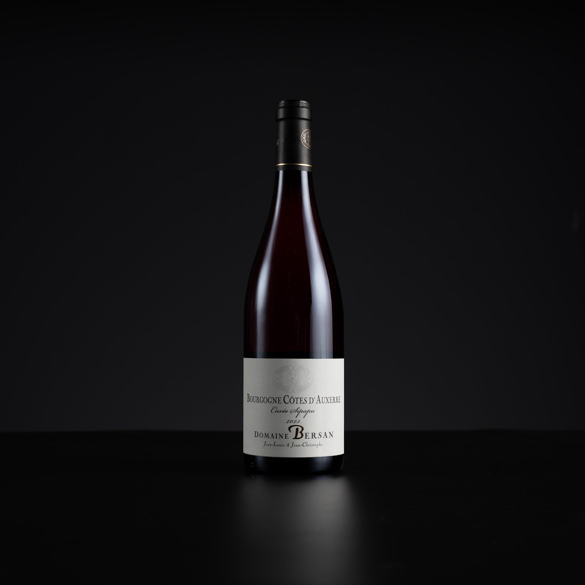 A single bottle of Domains Berlan Bourgogne Cotes d'Auvergne Gran Rey wine, featuring a dark glass bottle with a white label and black cap, set against a solid black background.