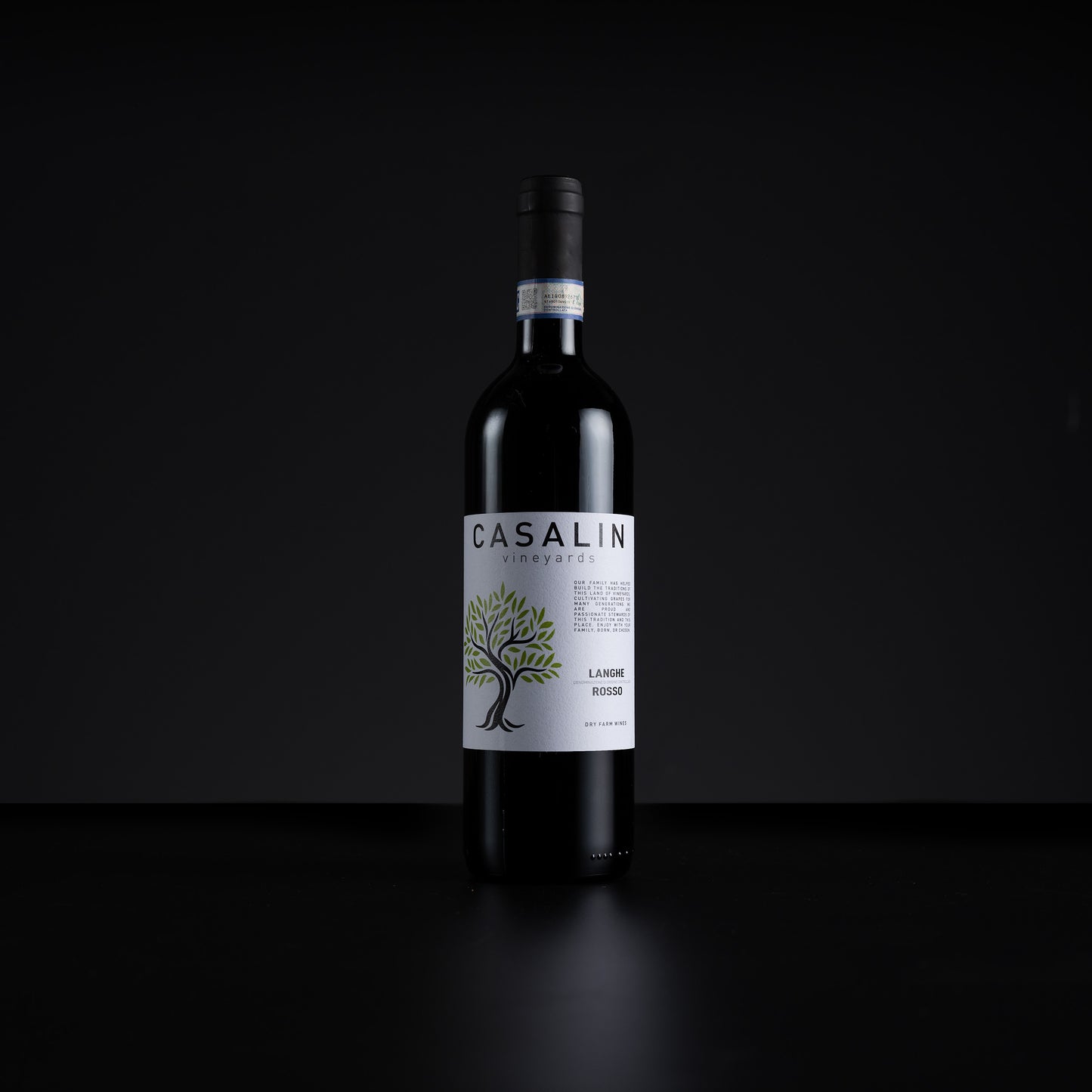 A single bottle of Casalin Vineyards La Vigna Rossa red wine stands centered against a dark black background. The bottle is dark glass with a white label featuring a green tree illustration and black text.