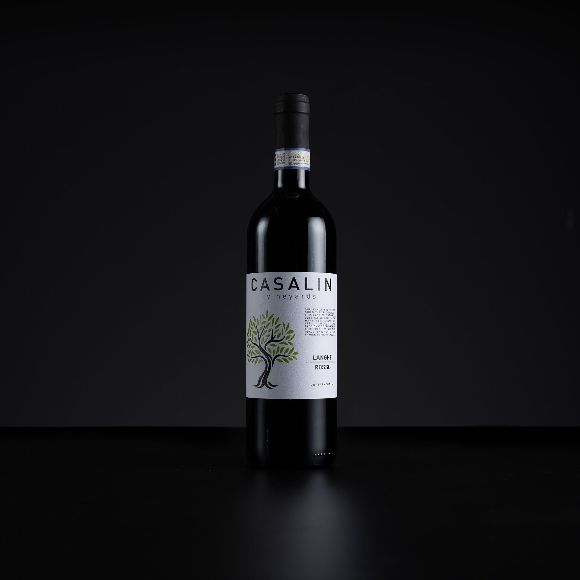 A single bottle of Casalin Vineyards La Vigna Rossa red wine stands centered against a dark black background. The bottle is dark glass with a white label featuring a green tree illustration and black text.