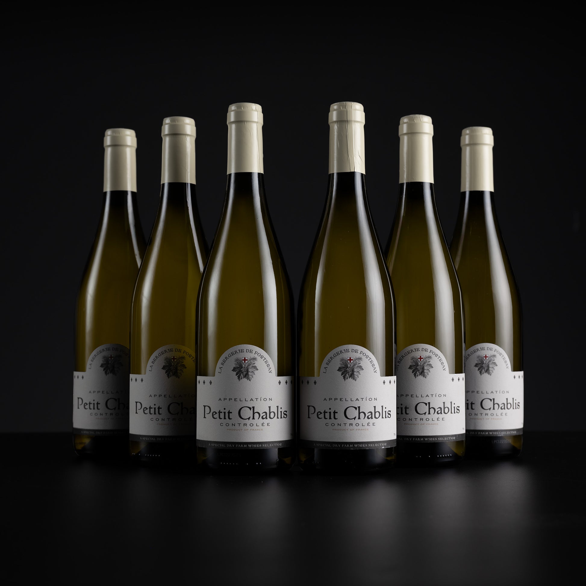 Six bottles of Petit Chablais Appellation White Wine arranged in a row against a dark black background.