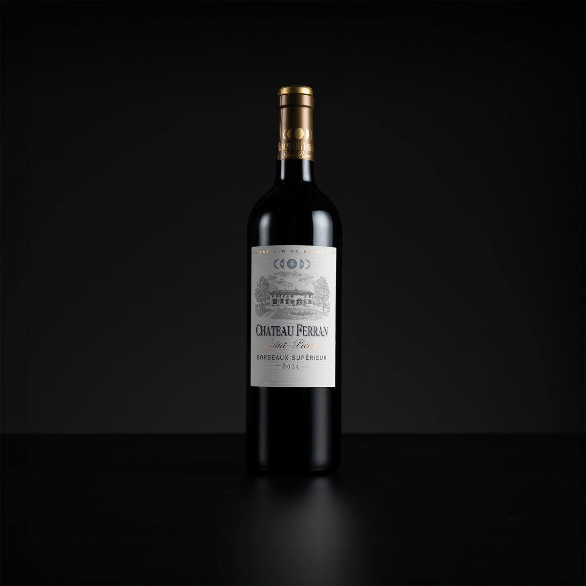 A single bottle of Chateau Ferran Saint-Beau Red (red wine) with a white label and gold foil, standing on a dark reflective surface against a black background.