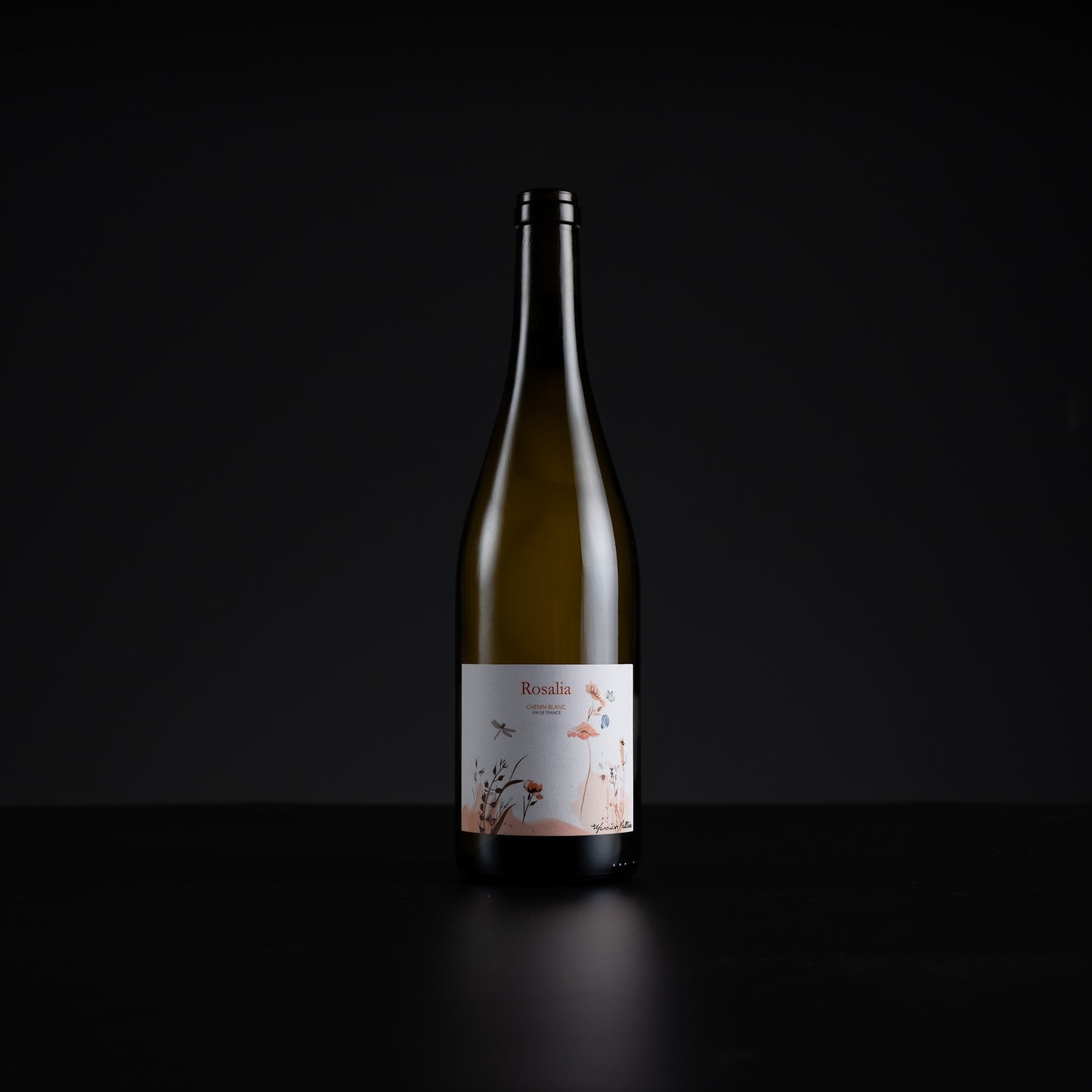 A single dark glass wine bottle with a white label featuring delicate pink floral illustrations, set against a solid black background.