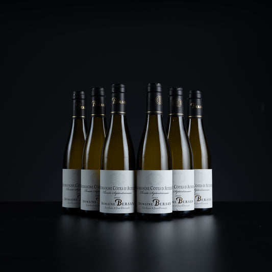 Six bottles of Dom Pérignon Grand Cru Bon Voyage white wine arranged in a row on a dark reflective surface against a black background.