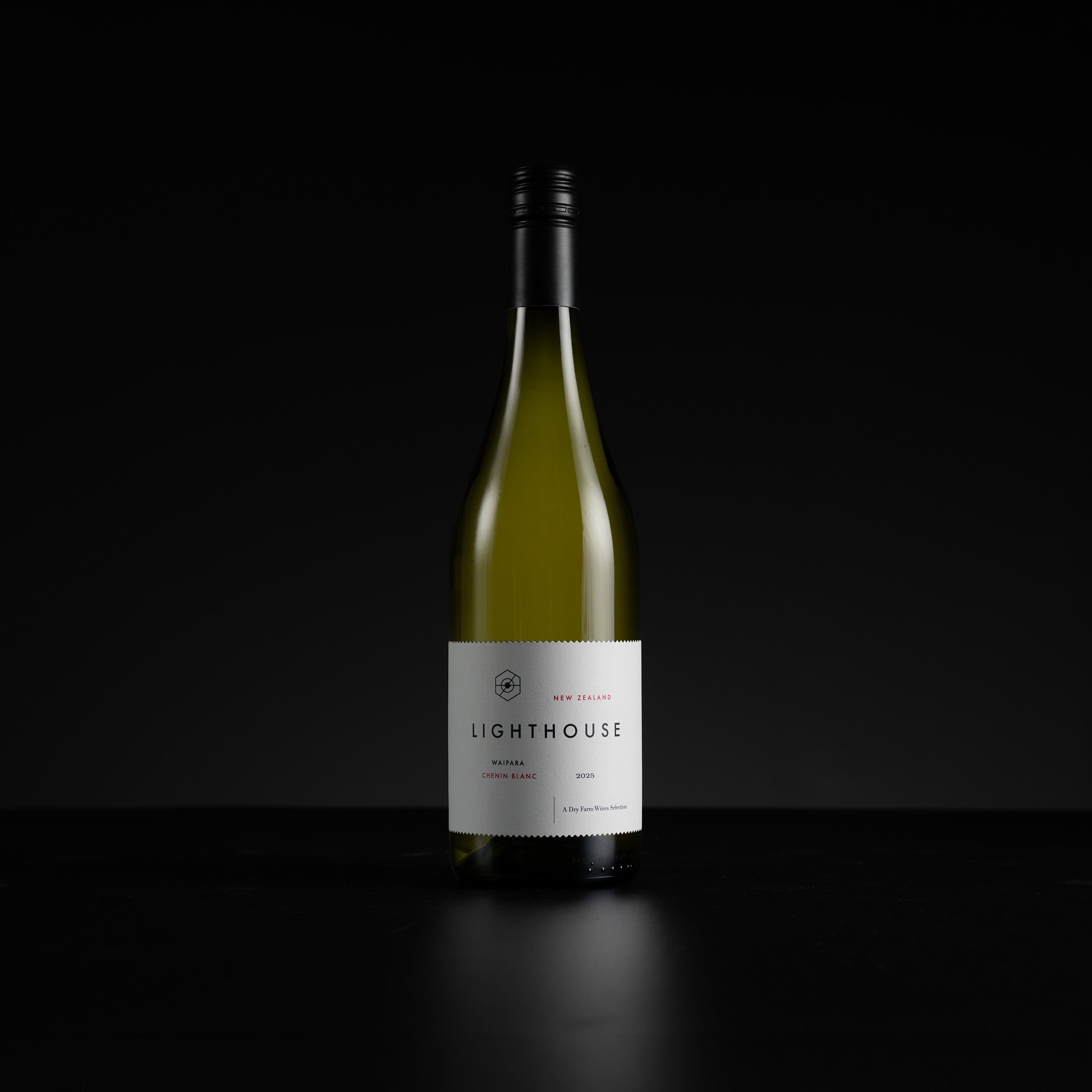 A single bottle of Lighthouse White Zinfandel standing upright on a dark surface against a black background. The bottle is pale green glass with a white label and a black screw cap.