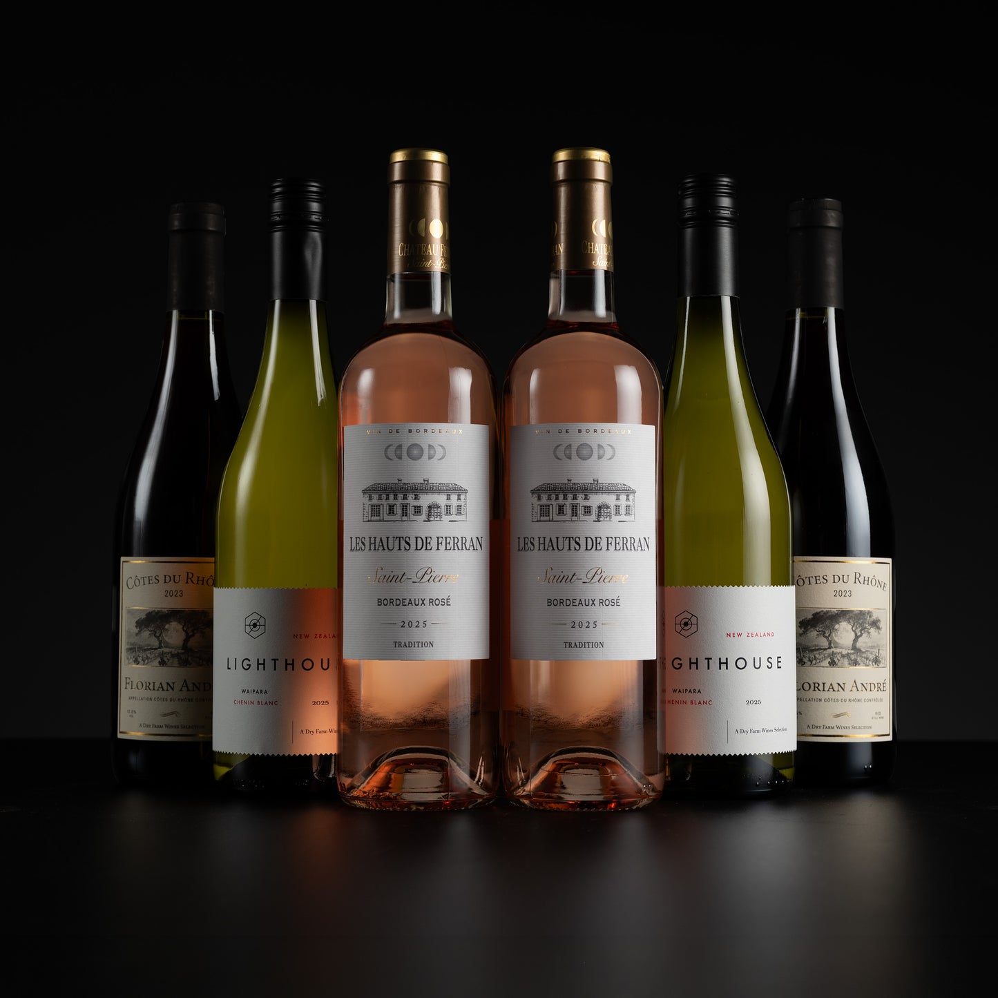 Six wine bottles from Les Hauts de Ferran are arranged in a row against a black background. The lineup includes dark red, pale green, pink, and white wines, with the two central rosé gins featuring gold foil caps and white labels with black text.
