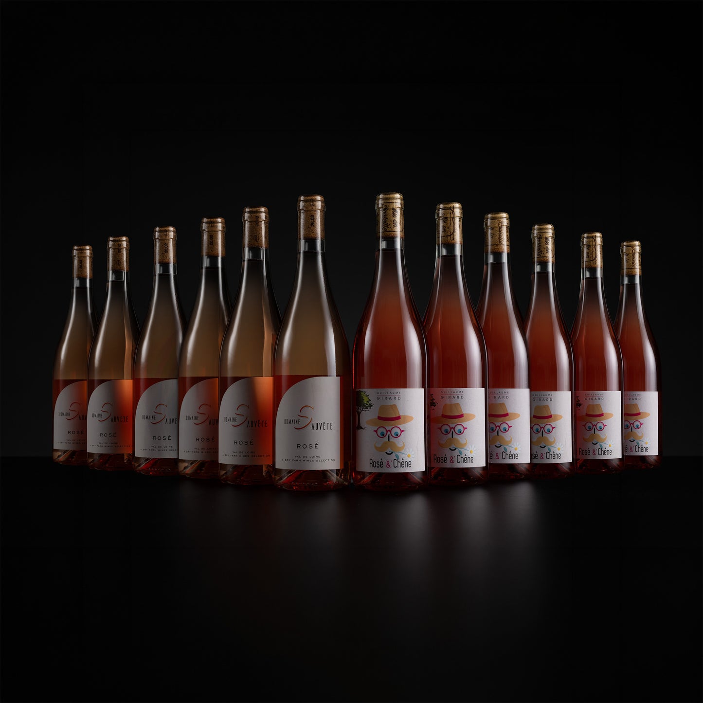 A row of ten glass rosé wine bottles with gold caps and white labels, arranged in a semi-circle on a black reflective surface against a black background. The labels feature the brand name 'Saint-Simon' and the cuvé 'Les Ducs'.