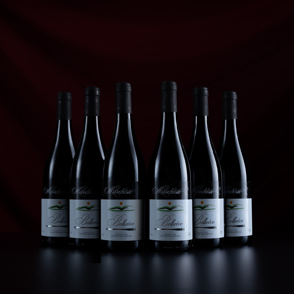 Six dark glass wine bottles with white labels and black capsules, arranged in a row against a dark red and black background. The labels show the brand name 'Moiroux' and the cuvé 'Béhère'.