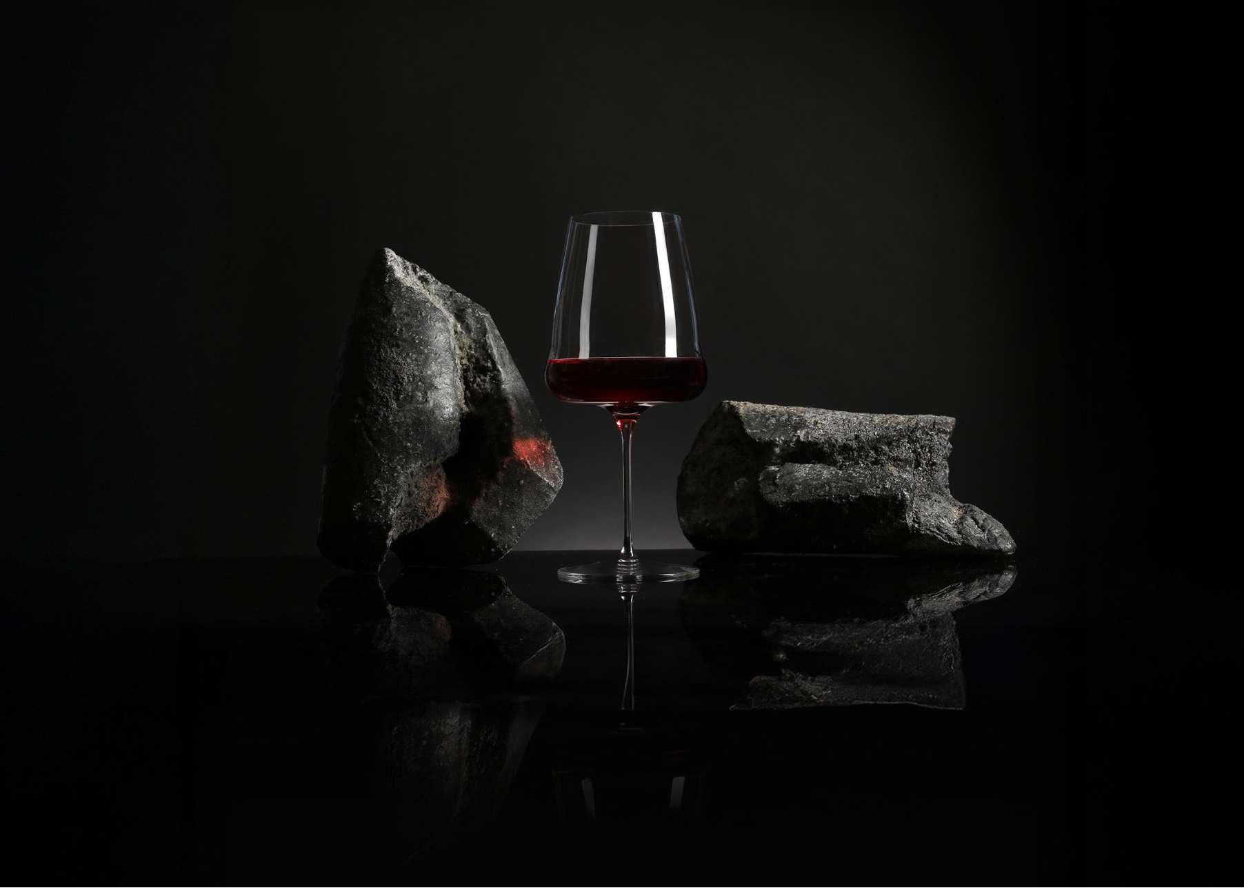 Glass of red wine on a rock with a dark background