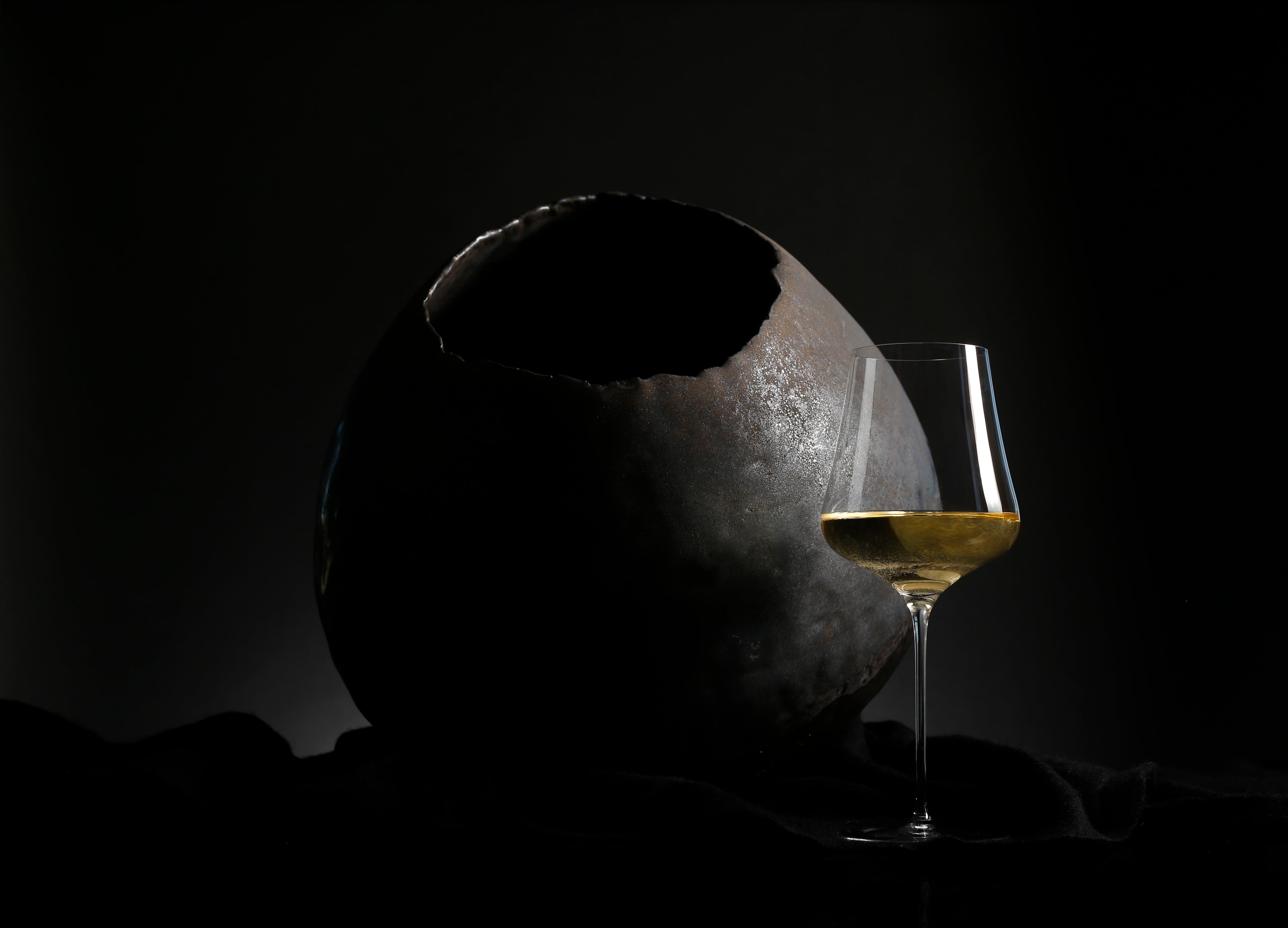 White wine with ceramic sphere on a dark background