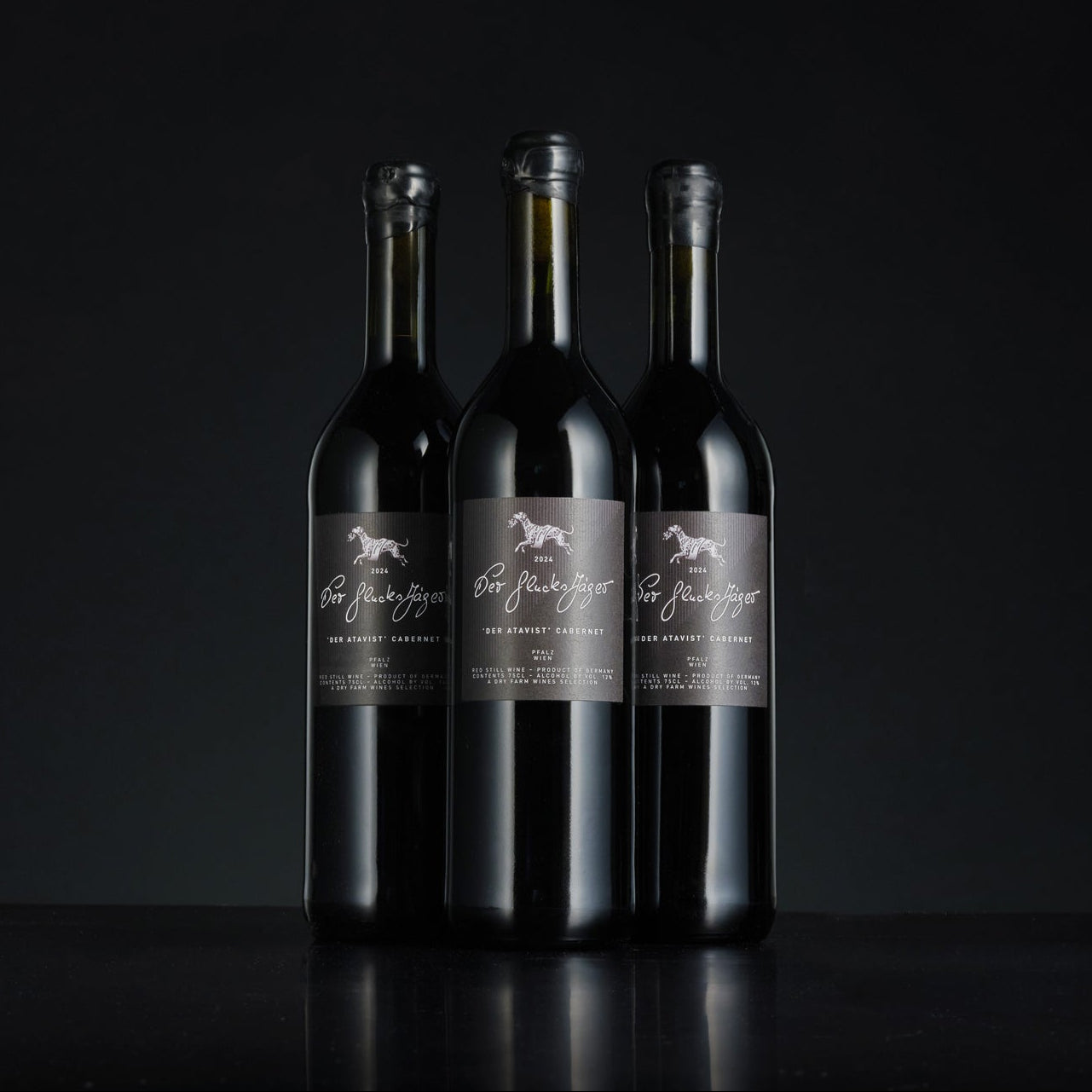 Three wine bottles with labels on a black background