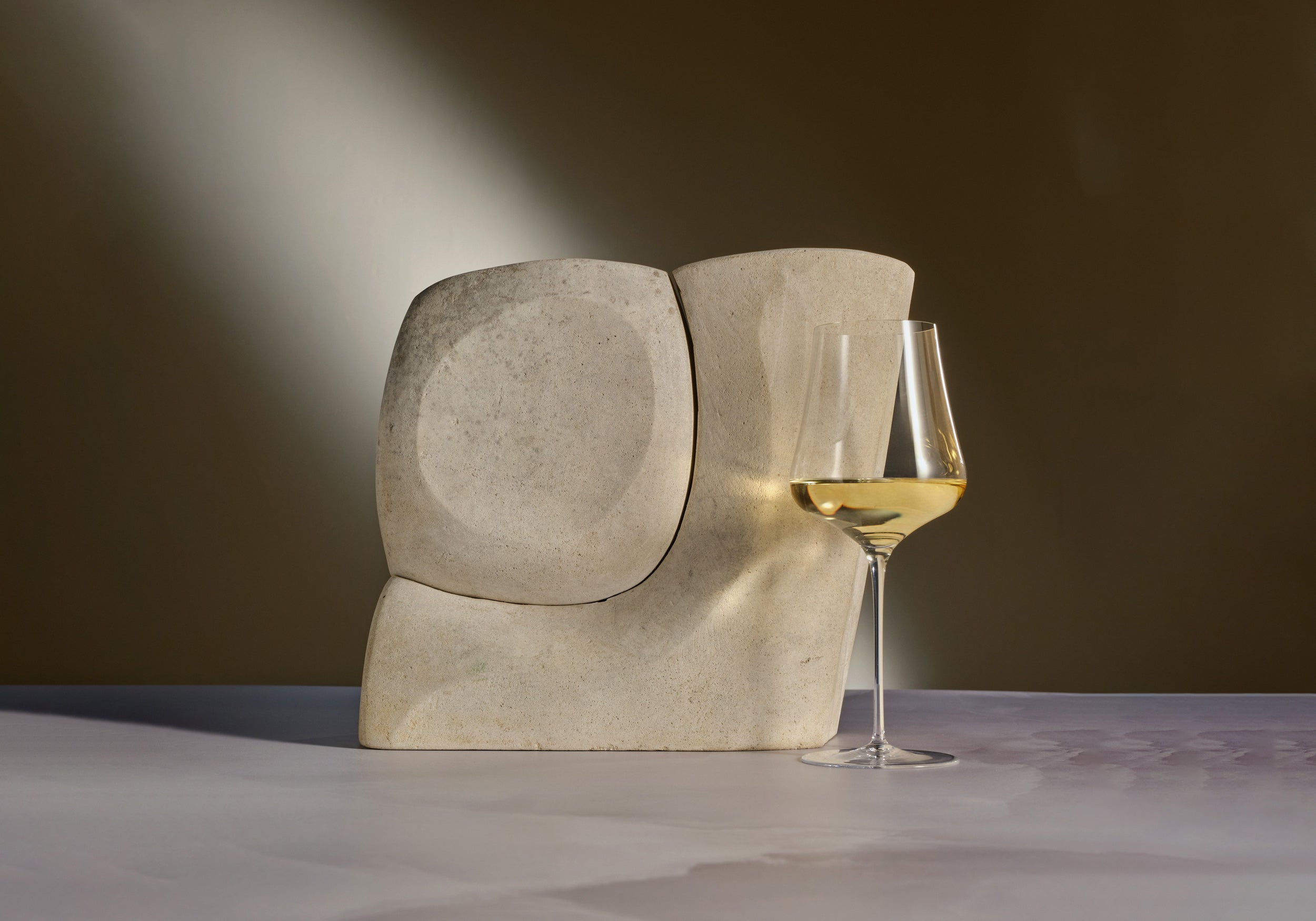 Concrete sculpture with a glass of white wine on a dark background