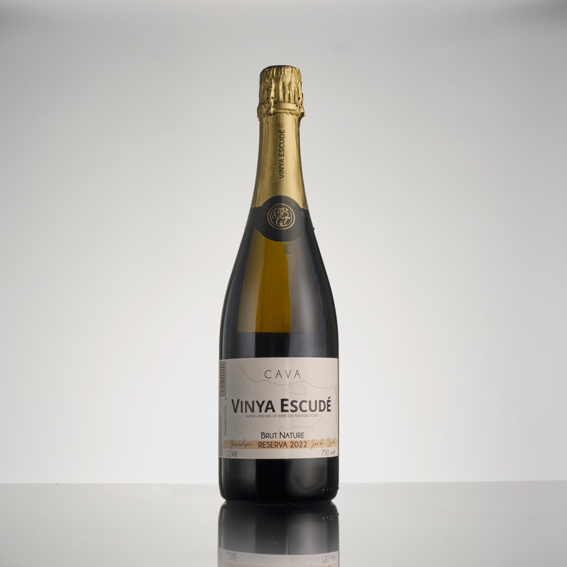 Bottle of Vinya Escude wine on a reflective surface with a gray background