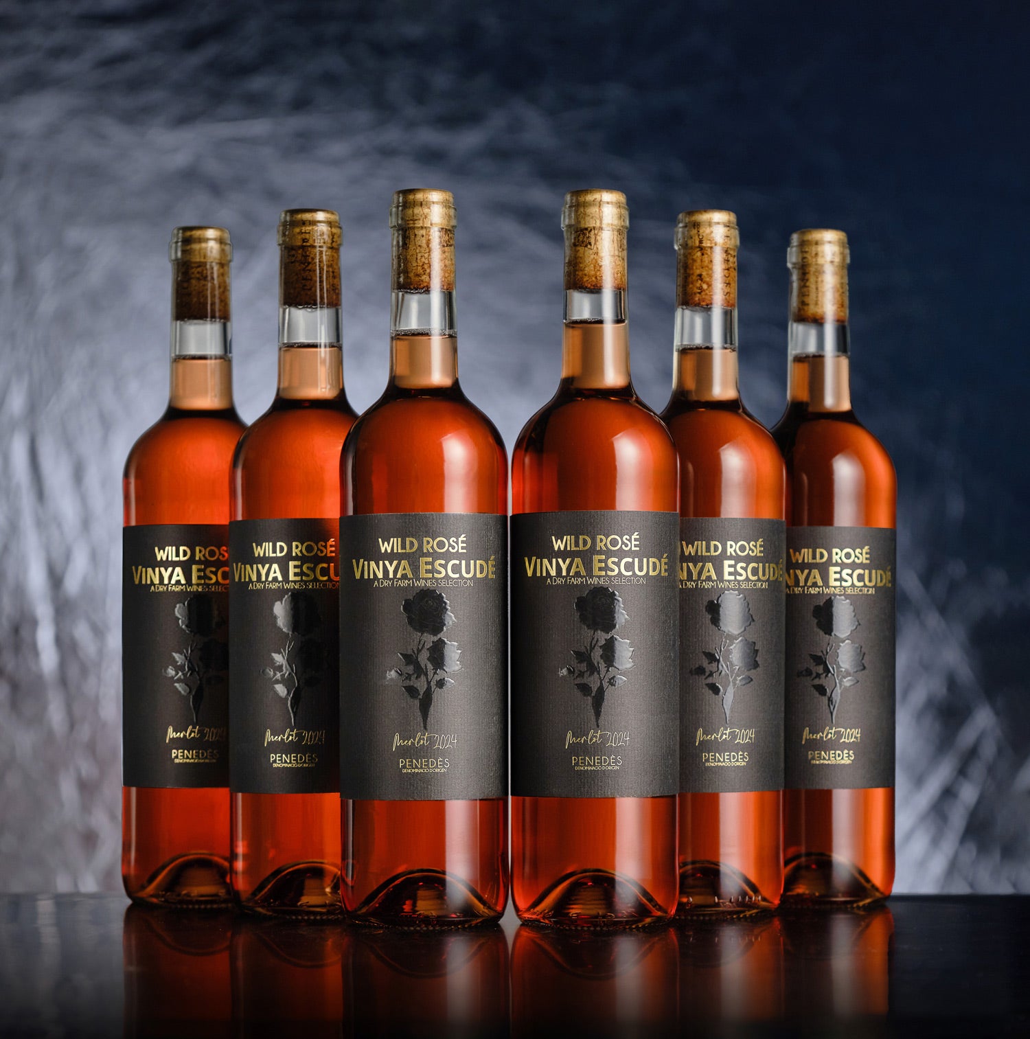 Six bottles of Wild Rosé Vinya Escudé wine on a dark background
