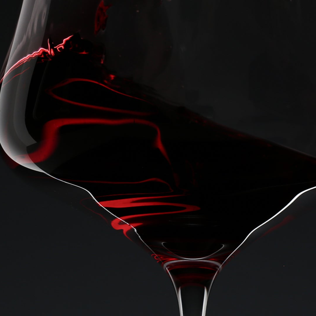 Close-up of a wine glass with red wine against a black background