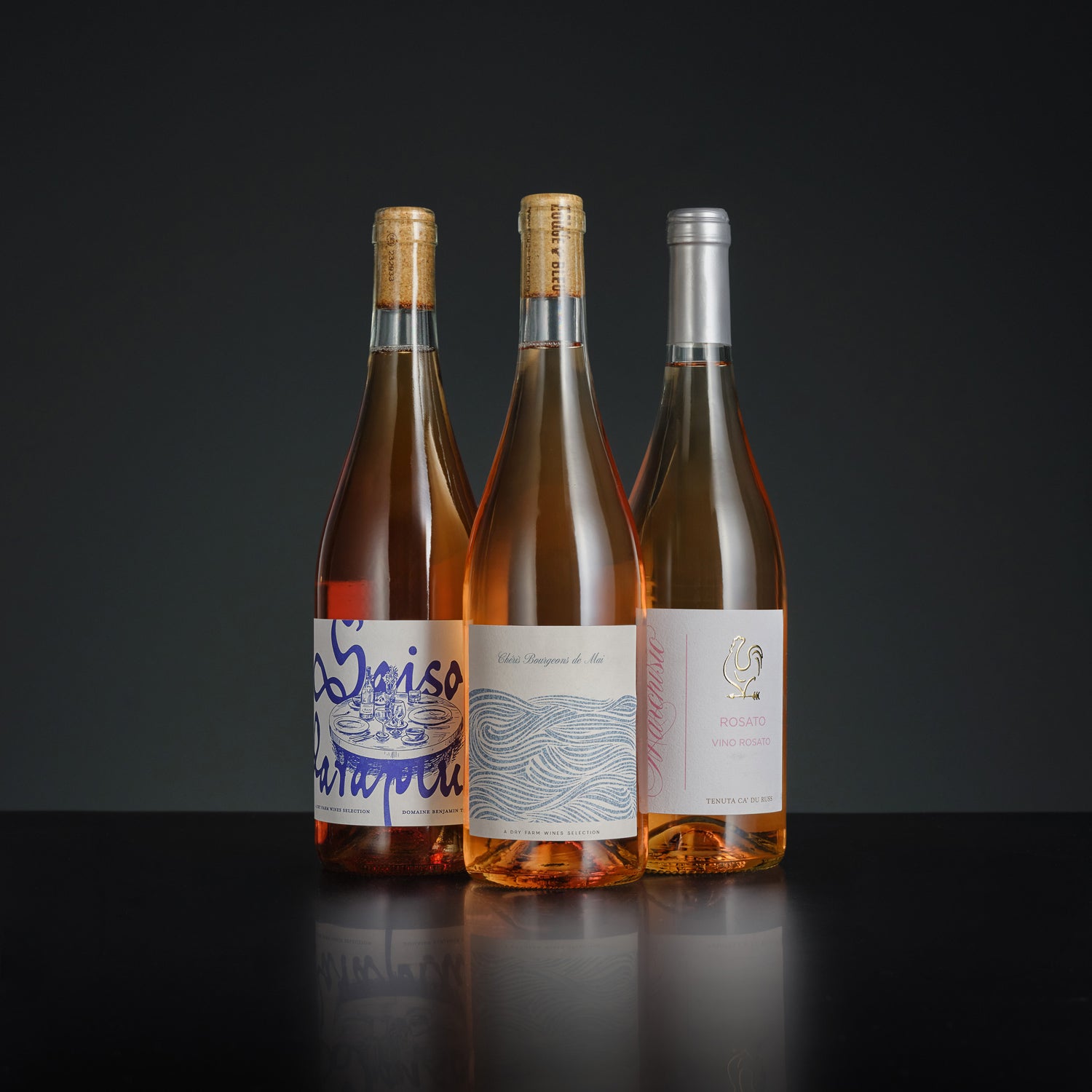 Three wine bottles with labels on a dark background